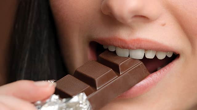 A close up of the woman's mouth eating chocolate