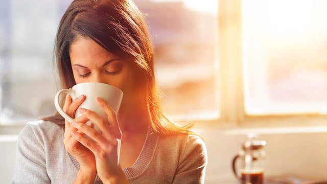 A young woman is drinking from the cup