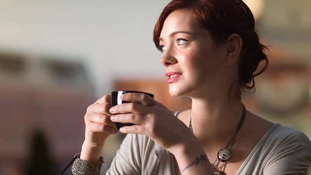 a woman is drinking coffee in a cafe