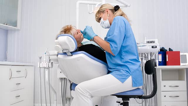 A dentist is checking on a patient in dental office