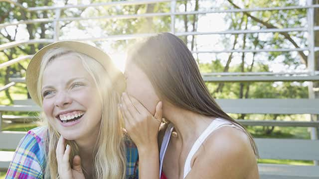 Teenage girl whispering to a friend