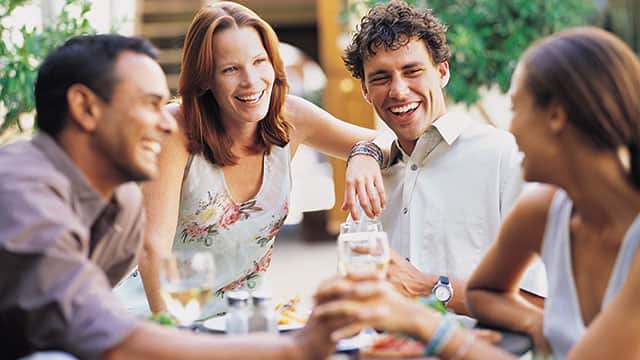 Two couples having a glass of wine in outdoors cafe
