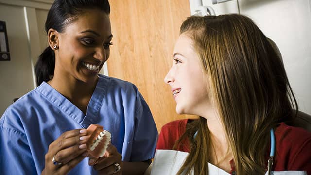 dental hygienist and patient looking at a mouth model