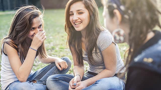A teenage girl wearing braces, laughing with friends