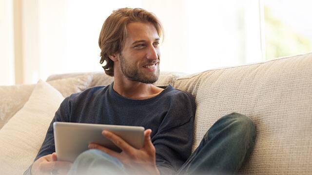 A man is using a tablet computer and smiling