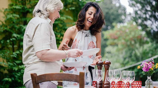 An older and a younger women preparing table outdoors