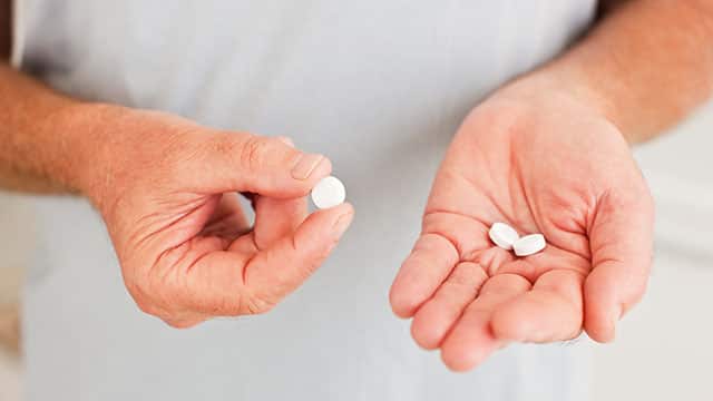 A close up of the man holding pills