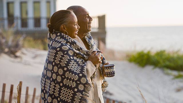 A middle age couple holding cups on the beach