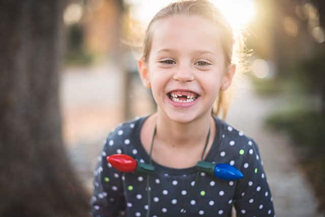 A small girl has a missing front tooth and smiling outdoors A small girl has a missing front tooth and smiling outdoors