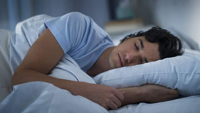 a man sleeping on the bed covered with blanket