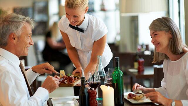 Waitress serving middle age couple at the restaurant Waitress serving middle age couple at the restaurant
