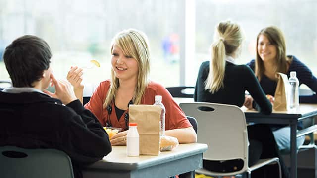 A woman is eating lunch in a cafeteria A woman is eating lunch in a cafeteria