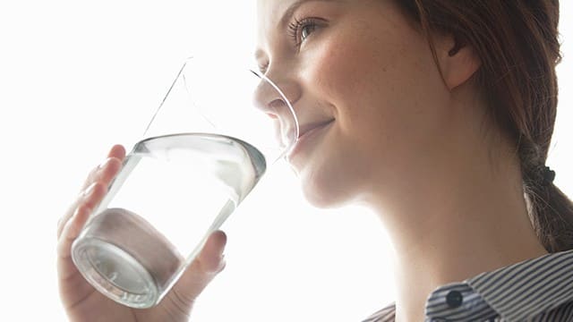 Mujer sonriente bebiendo un vaso de agua