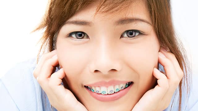 A close up of young woman's face wearing braces