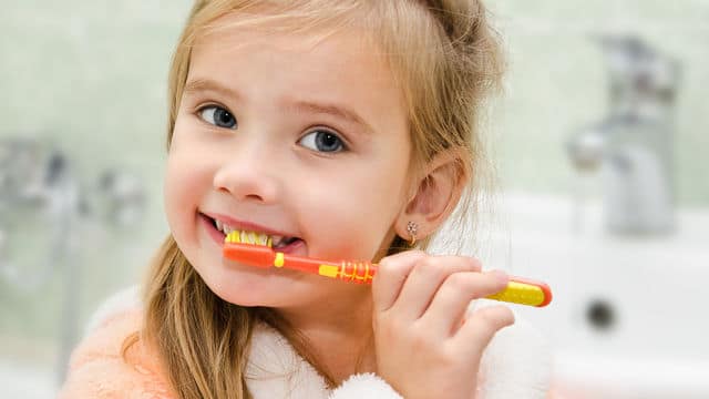 Niña pequeña sonriendo mientras se lava los dientes