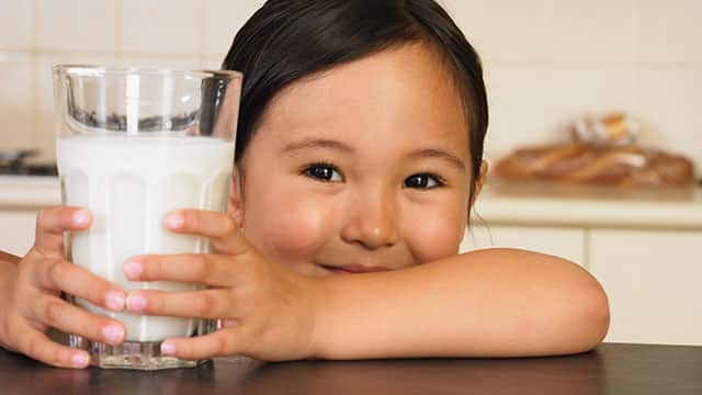 A little girl holding a glass of milk