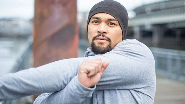 a man in grey sweatshirt is stretching outside