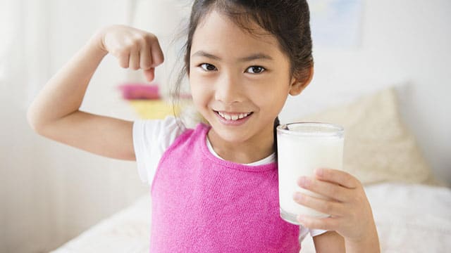 A girl holding a glass of milk inside