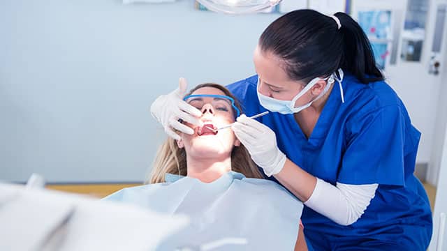 A dental hygienist checking on a patient in the dental office
