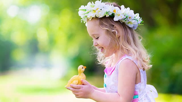 A little girl is holding a toy duck outdoors
