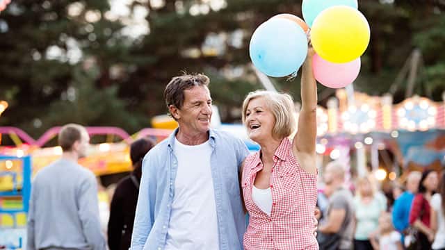 A senior couple having a good time and enjoying some balloons at the fair 