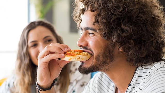 Man eating pizza with friend