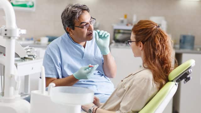A dentist talking with a patient about treatment in a dental office