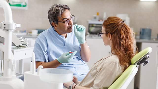 dentist in dental office talking with female patient