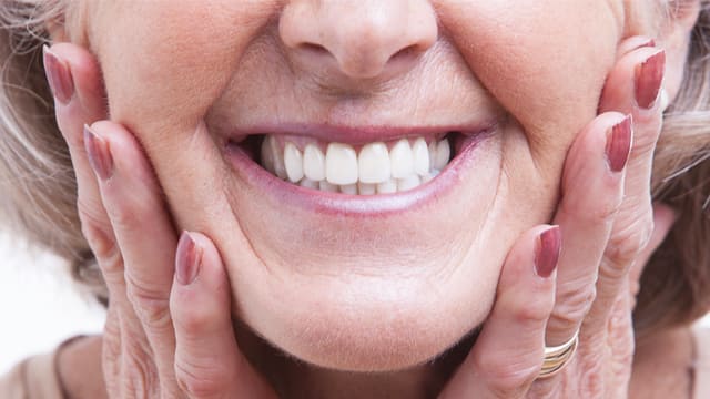 Mujer mayor con dentadura postiza y sonrisa blanca