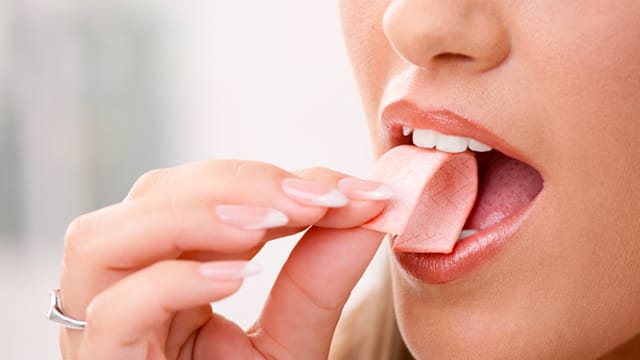 Woman putting chewing gum into her mouth