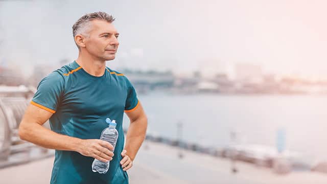 healthy athletic middle aged man with fit body holding bottle