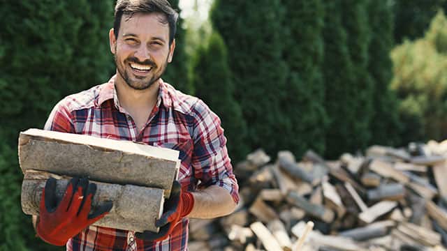A man chopping a wood outdoors while smiling