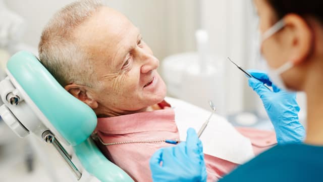 Female dentist about to examine a senior male patient