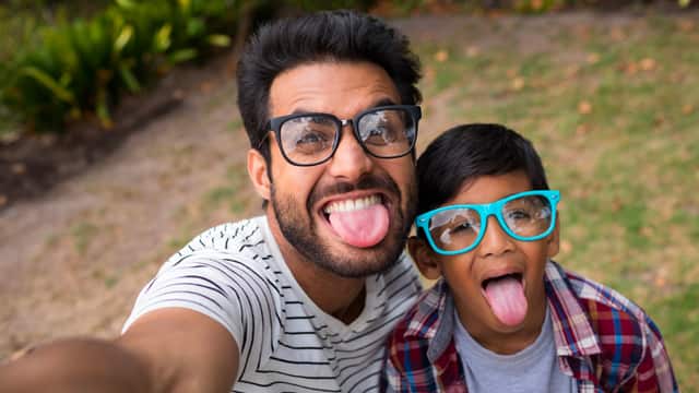 Father and son wearing glasses and sticking out their tongues taking a silly selfie