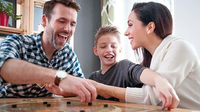 Happy family of three playing a board game at home