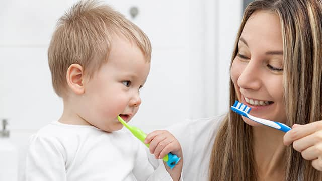 Happy mother teaching her baby how to bush teeth