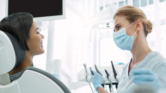 A female dentist talks with a female patient in a dental office
