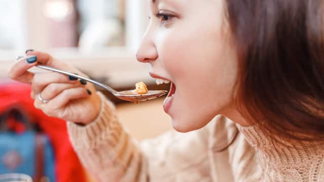 Profile of a young woman eating a bowl of soup