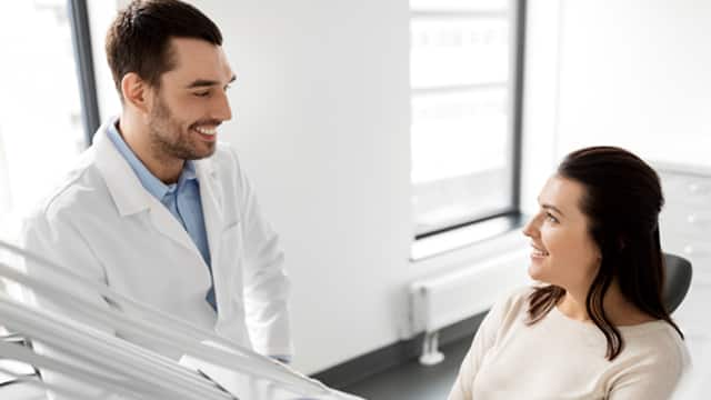 A male dentist talks with a female patient in a dental office