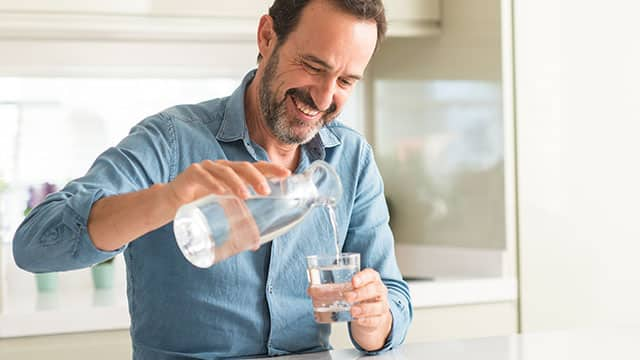 man pouring water in cup