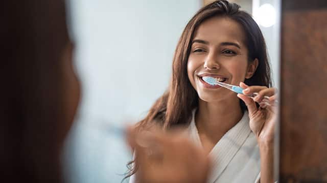 adult woman brushing her teeth in bathroom