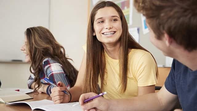 High School Students Sitting At Table Collaborating In Class Together