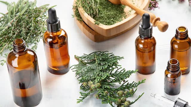 Five bottles of essential oils and herbs on a table