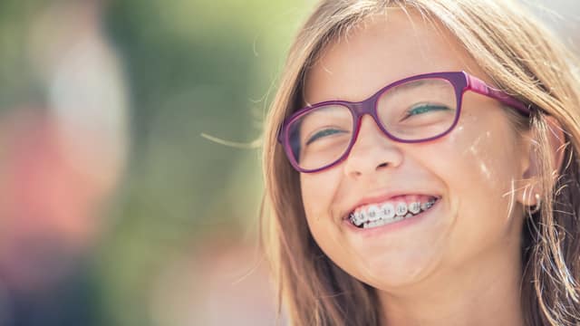 Young girl in purple glasses smiling with braces