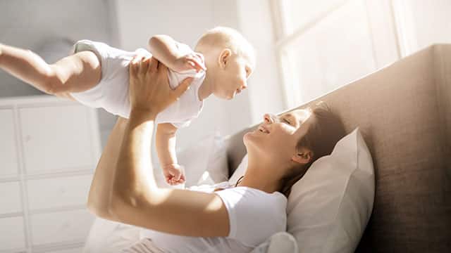 A mother with her baby on bed having good time