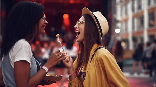 Two girls laughing and eating in a social setting
