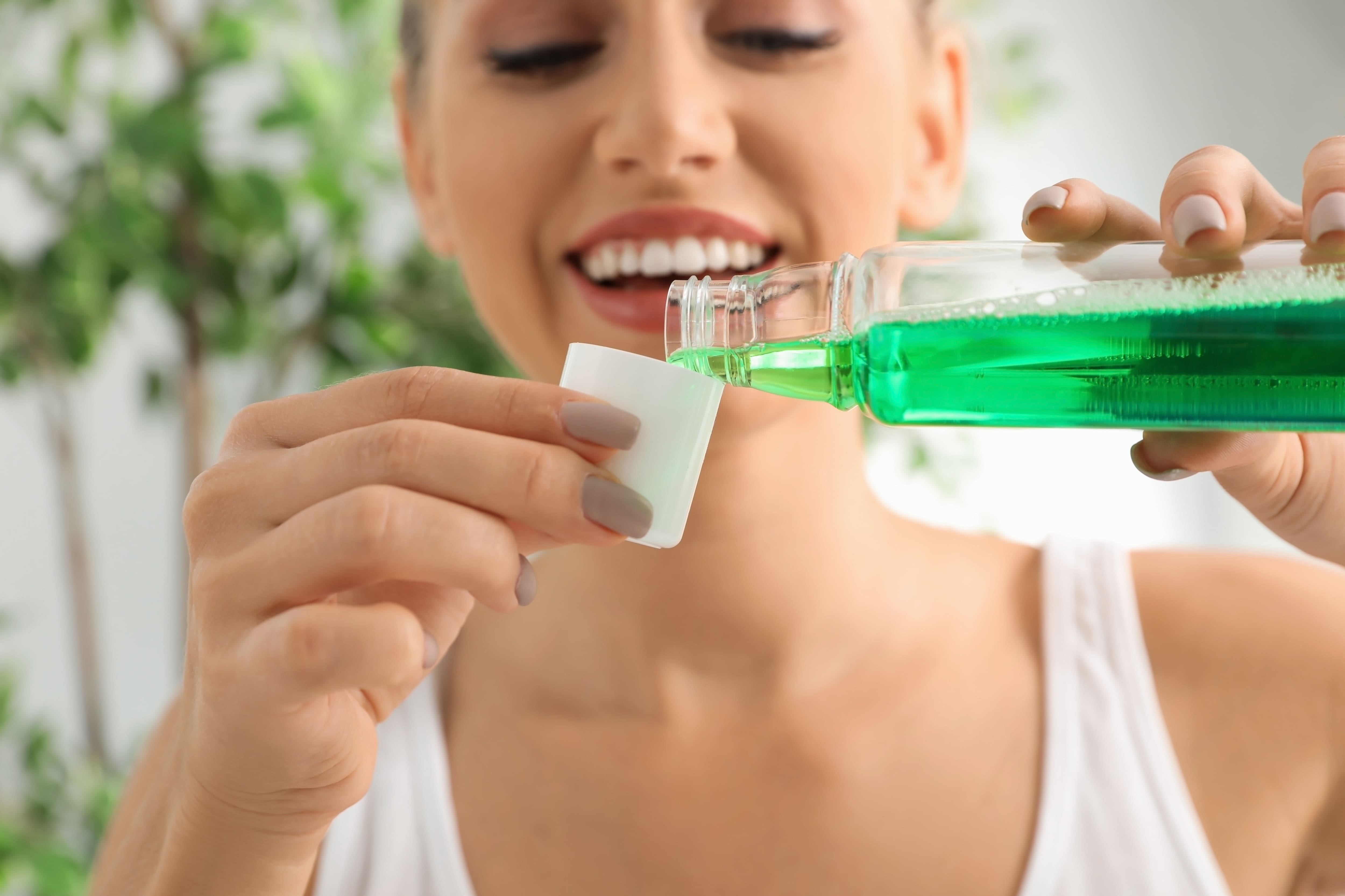 close-up of a woman pouring mouthwash from bottle into cap
