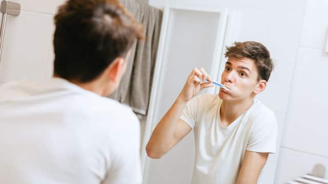 A teenager brushing teeth in a bathroom