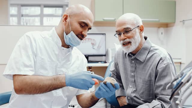 A male Prosthodontist talks with an elderly male patient