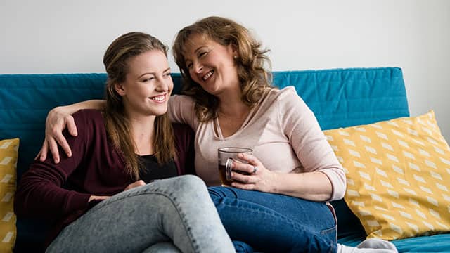 Mother and teen daughter sitting in a sofa at home